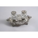 A SMALL VICTORIAN INKSTAND of shaped oval outline with a foliate border & two mounted cut-glass