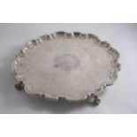 A GEORGE II "DUTY DODGER" SALVER with a shaped & moulded border, four large leafy scroll feet & an