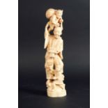 AN IVORY CARVING of a man with a demon on his shoulders and a boy at his feet, signed,  12ins. (30.