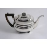 A GEORGE III BARGE-SHAPED TEA POT on ball feet, with a fluted knop finial, probably by John