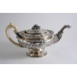 A GEORGE IV EMBOSSED TEA POT resembling the form of a classical lamp with a bird-mask spout, an