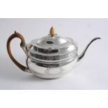 A MODERN ENGRAVED OVAL TEA POT in the George III style with two vacant trophy of arms cartouches and