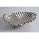 AN EDWARDIAN FLUTED SHELL-SHAPED DISH on three textured feet, maker's mark "GH", Sheffield 1909;