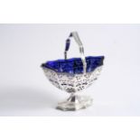 AN EDWARDIAN SWING HANDLED SUGAR BASKET on a shaped foot with pierced sides, reeded borders & a blue