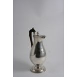 A GEORGE III BALUSTER HOT WATER JUG on a circular pedestal foot with reeded borders & a bud