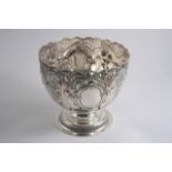 AN EDWARDIAN EMBOSSED ROSE BOWL on a domed circular foot with a pierced rim & two vacant cartouches,