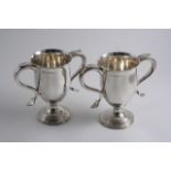 A PAIR OF VICTORIAN LOVING CUPS on reeded pedestal bases with twin scroll handles, by Hawkesworth,