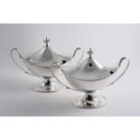 A PAIR OF LATE VICTORIAN SAUCE TUREENS on oval pedestal bases with domed covers, loop handles &