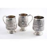 THREE 20TH CENTURY INDIAN MUGS embossed & chased with native figures & scenes, with Art Deco