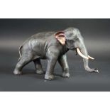 A BRONZE FIGURE OF AN ELEPHANT with naturalistically engraved skin and set with ivory tusks, signed,