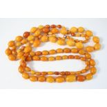 A GRADUATED AMBER BEAD NECKLACE formed with graduated oval-shaped beads, 96cm. long, 73 grams,