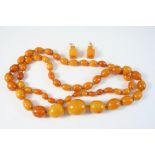 A SINGLE ROW GRADUATED AMBER BEAD NECKLACE 94cm. long, 82 grams, together with a pair of amber