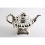 A VICTORIAN TEA POT of inverted baluster form with fluting, ornate feet, a C-scroll handle & a