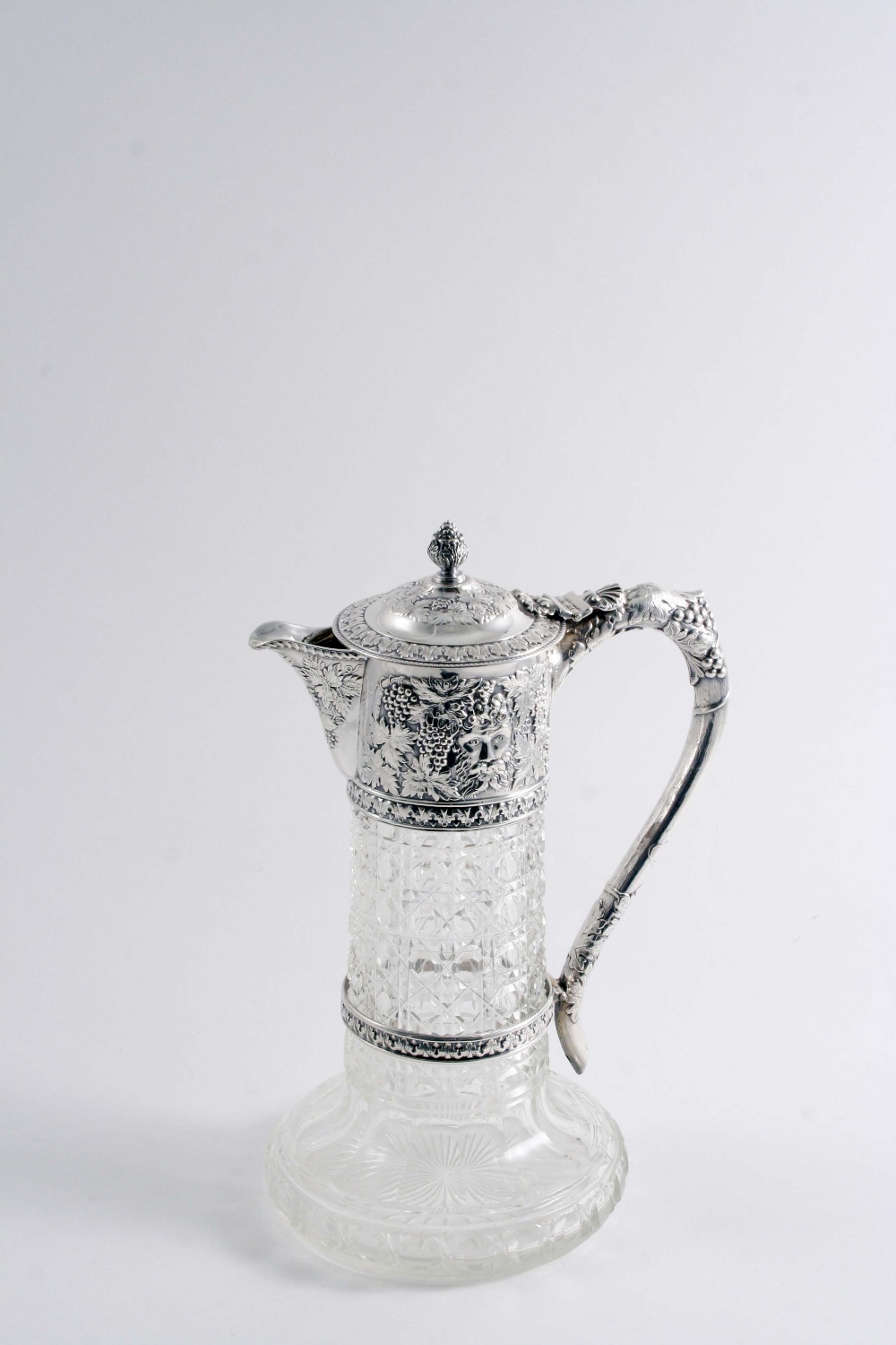 AN EDWARDIAN MOUNTED CUT-GLASS CLARET JUG decorated in low relief around the mount with fruiting