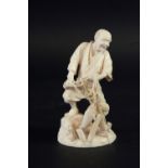 AN IVORY FIGURE OF A FISHERMAN on a rocky outcrop, 5 3/4ins. (14.5cms.) high