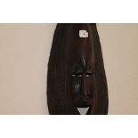 A NATIVE HARDWOOD MASK. An African mask in a brown hardwood, with dual faces and geometric carved