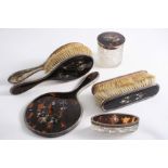 A FIVE PIECE MOUNTED TORTOISESHELL DRESSING TABLE SET comprising hand mirror, two clothes