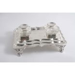 A MODERN INKSTAND  of shaped rectangular outline with a laurel leaf & berry border & two mounted