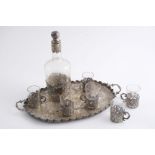 A CONTINENTAL LIQUER SET including a decorative oval tray, a mounted cut-glass decanter & stopper