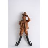 A BLACK FOREST CARVED WOODEN NOVELTY COAT HOOK in the form of a gentleman in breeches, doffing his