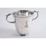 AN EDWARDIAN CUP of campana form with twin bird mask handles, a conical foot & an engraved