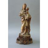 AN ALABASTER FIGURE OF THE MADONNA AND CHILD on a bow front plinth carved in high relief, with a