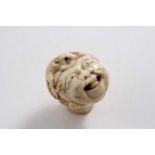 A 19TH CENTURY CARVED IVORY KNOP OR STICK MOUNT in the form of a grotesque male mask with a cap &