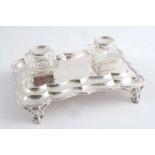 A MODERN INKSTAND  of shaped rectangular outline with a laurel leaf & berry border & two mounted
