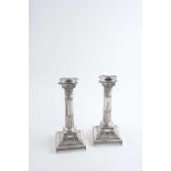 A PAIR OF EDWARDIAN CORINTHIAN COLUMN CANDLESTICKS on decorative, bevelled square bases,