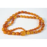 A SINGLE ROW GRADUATED AMBER BEAD NECKLACE set with oval-shaped beads, 66cm. long, 36 grams.