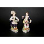 PAIR OF OF DERBY FIGURES of two seated young figures, brightly painted with one holding flowers