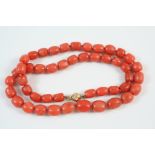 A CORAL BEAD NECKLACE formed with graduated barrel-shaped coral beads to a gold ball clasp, 46.