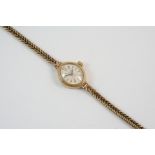 A LADY'S 9CT. GOLD WRISTWATCH the oval shaped dial with dagger numerals, on an integrated