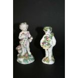 TWO DERBY FIGURES of Putti, the figures holding a basket of flowers and the other a bird and flower.