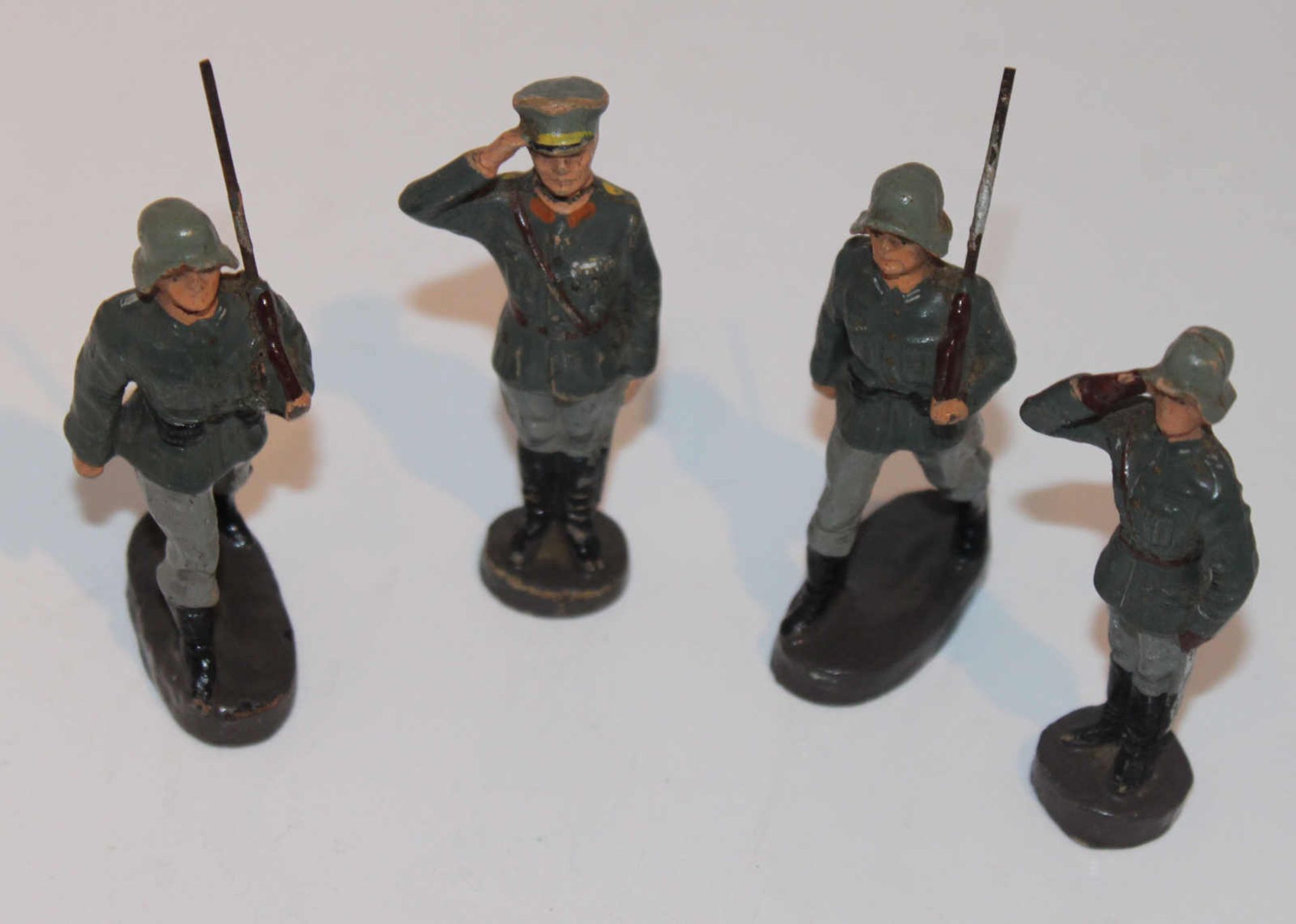 4 Masse-Soldaten, ungemarkt, 7,5 cm Serie, dabei 2 Marschierer, 1 Offizier "Zum Gruß" sowie 1