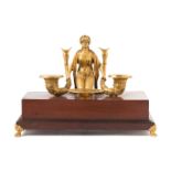 * An Empire Style Gilt Bronze Mounted Mahogany Figural Encrier   the robed maiden kneeling,