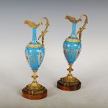 A pair of late 19th century Continental porcelain and ormolu mounted ewers, with gilded scroll and