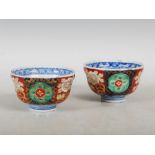 A pair of Japanese Imari rice bowls, the exteriors with floral panelled decoration, the interiors