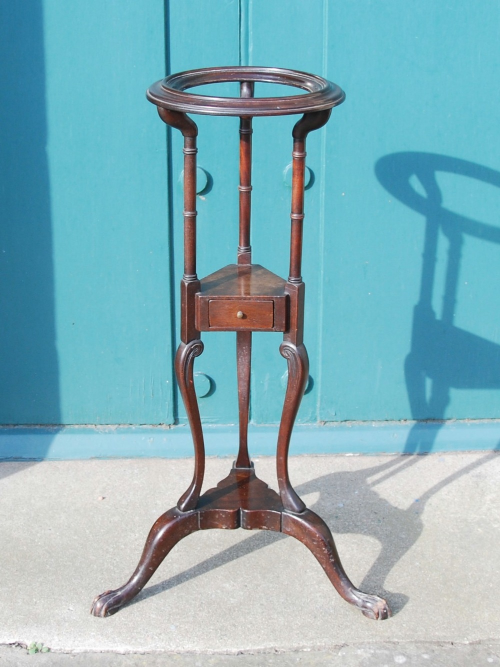 A George III style mahogany washstand, the open circular top raised on turned columns above a