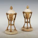 A pair of late 19th century marble and gilt metal mounted urns, with flame finial, raised on three