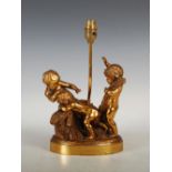 An early 20th century bronze table lamp, cast with three putti on an oval plinth base, overall 31.