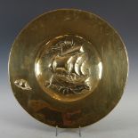 A Scottish Arts & Crafts brass charger, with embossed decoration of galleon and conch shell, 53cm