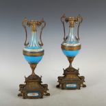 A pair of bronzed spelter and porcelain twin handled urns, decorated with a horizontal border of