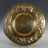 A Scottish Arts & Crafts brass charger, decorated with an embossed border of stylised butterflies,