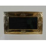 A Scottish Arts & Crafts brass overmantel mirror, the bevelled rectangular mirror plate within an