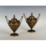 A pair of late 19th century bronze twin handled urns and covers, the tapered cylindrical urns