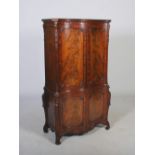 A George III style mahogany serpentine cupboard, the moulded cornice and dentil frieze above a