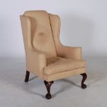 A George III style wing armchair, the upholstered back, arms and seat with loose cushion, raised