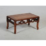 A Chinese dark wood low table, Qing Dynasty, the panelled rectangular top above a pierced frieze,