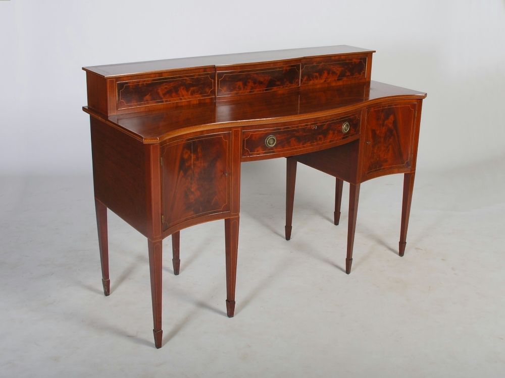 An Edwardian mahogany and boxwood lined serpentine sideboard, the upright stage back with two